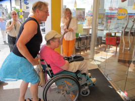 Monika Waldemair und Anita Liebs versuchen, mit dem Rollstuhl in die Filiale der Vollwertbäckerei Schneider in der Augsburger Straße zu kommen